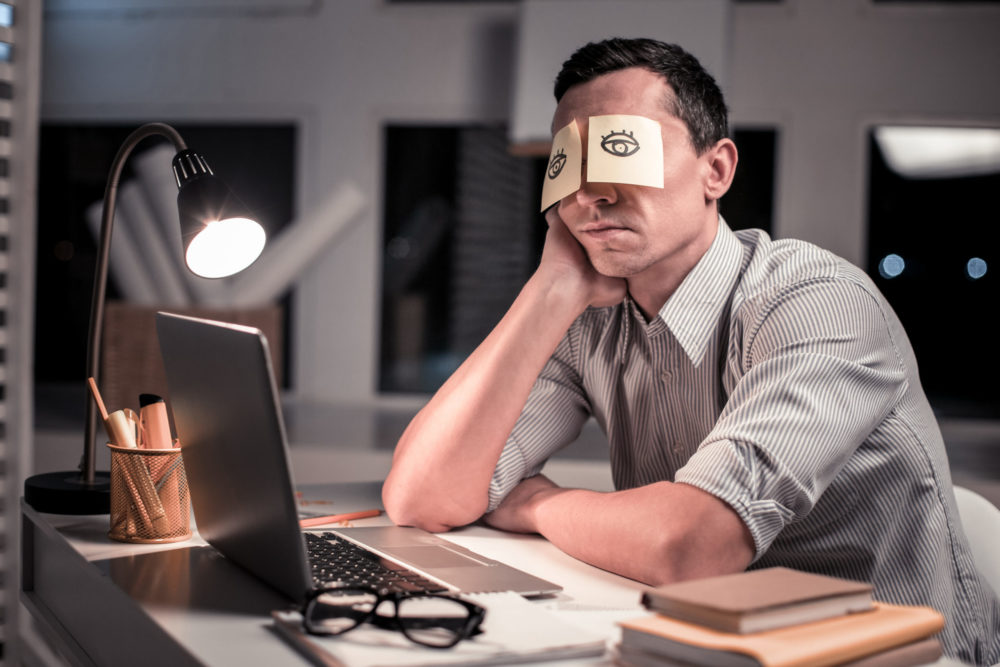 Pleasant tired man sitting at the table in the office